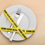 A plate with a fork and knife wrapped in yellow crime scene tape