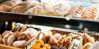 A display case filled with various types of baked goods including breads and pastries