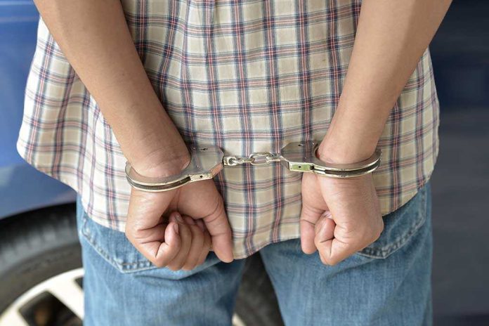 shutterstock_215366989.jpg A person in handcuffs viewed from behind, wearing a plaid shirt and denim jeans