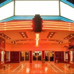 Entrance of a vintage movie theater illuminated by neon lights at night