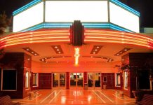 Entrance of a vintage movie theater illuminated by neon lights at night