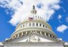The U.S. Capitol building with an American flag flying in front against a blue sky