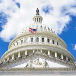 The U.S. Capitol building with an American flag flying in front against a blue sky