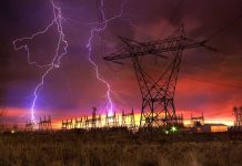 Lightning strikes illuminate a power station against a colorful sunset sky