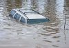 100,000 EVACUATED – Catastrophic Flooding Wrecks State A partially submerged vehicle in floodwaters