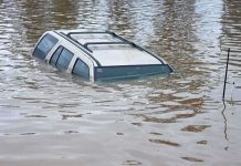 100,000 EVACUATED – Catastrophic Flooding Wrecks State A partially submerged vehicle in floodwaters