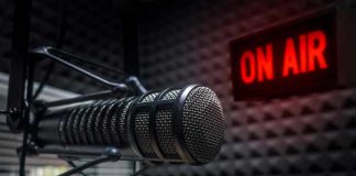 Microphone in soundproof studio with On Air sign.