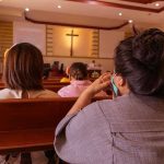 People sitting in church pews during service.