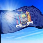 Mamdani’s Admin Blasts Home Ownership as ‘White Supremacy’ New York state flag waving against a blue sky