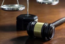 Gavel and scales of justice on wooden table.