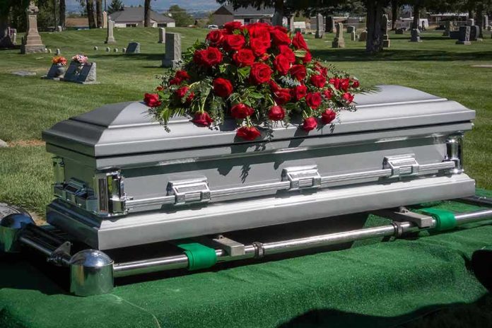 Silver casket with red roses in a cemetery.