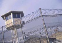 Guard tower behind barbed wire fence in a prison.