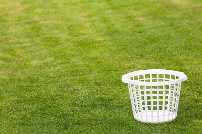An empty white laundry basket placed on green grass