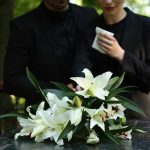 Long-Serving Congressman Dies Aged 86! Mourners in black holding white flowers at funeral.