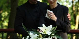 Long-Serving Congressman Dies Aged 86! Mourners in black holding white flowers at funeral.