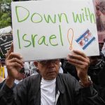Person holding Down with Israel sign at protest.