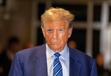 Man in blue suit and striped tie, serious expression.
