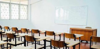 Empty classroom with desks, chairs, and whiteboard.