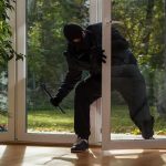 Homeowner GUNS DOWN Squatter – Faces Charges! A burglar in dark clothing entering a house through a glass door