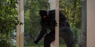 Homeowner GUNS DOWN Squatter – Faces Charges! A burglar in dark clothing entering a house through a glass door