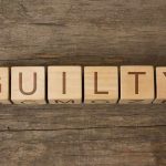 Wooden blocks arranged to spell 'GUILTY' on a wooden surface