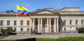 Historic building with Colombia flag in front.