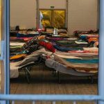 Berkeley Nightmare EXPOSED Inside The Dorms! Interior view of a temporary shelter with rows of beds.
