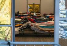 Interior view of a temporary shelter with rows of beds.