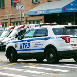 Police car and ambulances outside emergency room entrance.