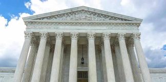 Justice Barrett BETRAYS Trump Again, 5-4 Vote! Building with columns under a cloudy sky.