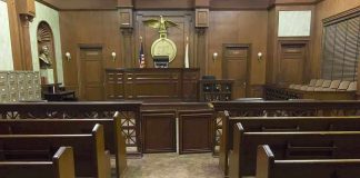 Interior view of an empty courtroom with wooden benches and a judges bench