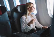 Passenger with headphones seated by airplane window