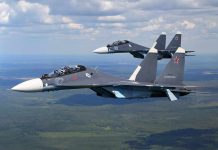Two fighter jets flying in formation over landscape