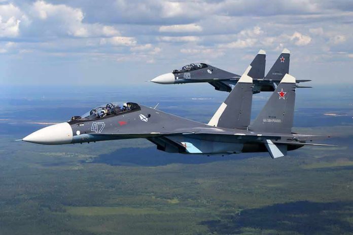 shutterstock_1457897060 Two fighter jets flying in formation over landscape