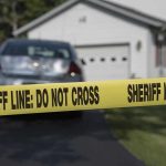 Sheriff line tape blocking a suburban driveway