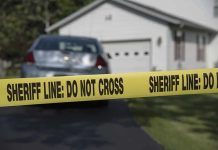 Sheriff line tape blocking a suburban driveway