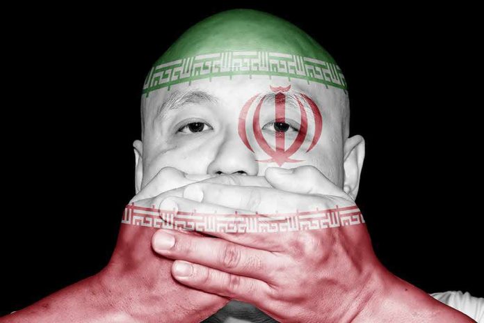 shutterstock_773225167 person with hands over mouth and Iran flag overlay