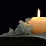 Candle on an open book with white flowers
