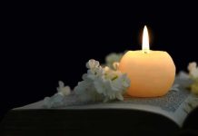 Candle on an open book with white flowers