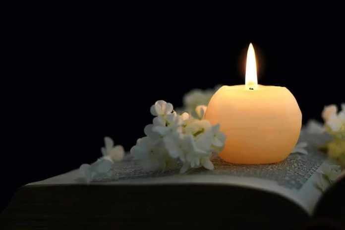 Candle on an open book with white flowers