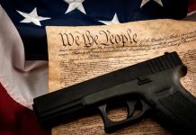 Handgun on U.S. Constitution with American flag backdrop