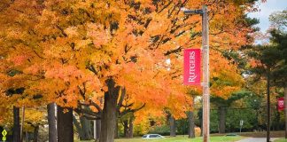 University Dean ARRESTED In Upskirt Sting Operation Autumn trees along a campus pathway with red banners on poles