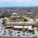historic mosque with domes and minaret overlooking a busy city square
