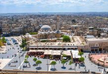 historic mosque with domes and minaret overlooking a busy city square