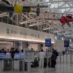airport security checkpoint with passengers and hanging vintage airplanes