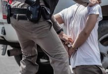 police officer handcuffing a person beside a vehicle