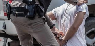 police officer handcuffing a person beside a vehicle