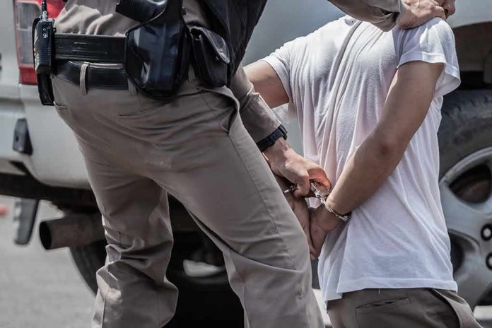 shutterstock_1705187374 police officer handcuffing a person beside a vehicle