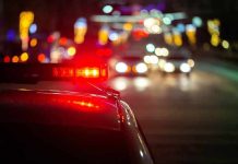 Police car with flashing red lights on a city street at night