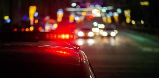 Police car with flashing red lights on a city street at night